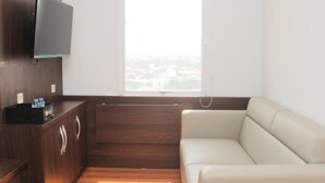 Ein modernes Zimmer mit einem Holzkasten, einem Flachbildfernseher, einer Couch und einem Fenster mit Blick auf die Stadt.