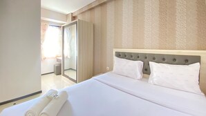 A hotel room with a large bed, a wardrobe, and a bathroom visible through an open door. - Cozy And Serene 2Br Apartment At Parahyangan Residence (Bandung)