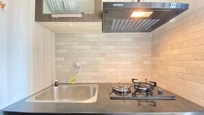 A kitchen with a stainless steel sink, a gas stove, and a modern range hood. - Cozy And Serene 2Br Apartment At Parahyangan Residence (Bandung)