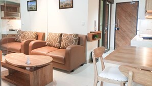Un salon moderne avec un canapé en cuir marron, une table basse en bois et une table à manger avec des chaises.