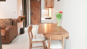 Un salon moderne avec une table à manger en bois, deux chaises, un canapé et un vase rempli de fleurs.