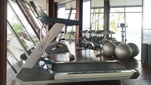 Une salle de sport équipée d’un tapis de course, d’haltères et de ballons d’exercice.