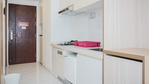 Una cocina moderna con armarios blancos, encimera de madera, un contenedor rosa y un lavavajillas blanco.