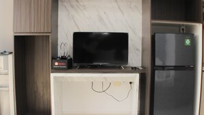 A kitchen with a built-in TV, a refrigerator, and a travel appliance on the countertop. - Nice And Comfy Studio West Vista Apartment (Jakarta)