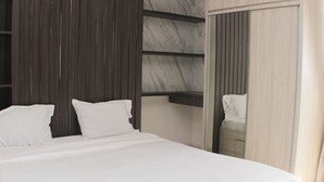 A modern hotel room with a large bed, a wooden panel wall, and a marble accent wall. - Nice And Comfy Studio West Vista Apartment (Jakarta)