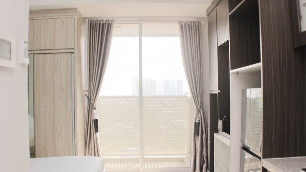 A modern hotel room with a bed, wardrobe, and a balcony with curtains. - Nice And Comfy Studio West Vista Apartment (Jakarta)