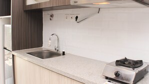 A modern kitchen with a stainless steel sink, a gas stove, and wooden cabinets. - Nice And Comfy Studio West Vista Apartment (Jakarta)
