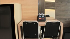 A hotel room with a wooden cabinet, a minibar, and a complimentary food and beverage sign. - Comfort 1Br At Sky Terrace Apartment (Jakarta)