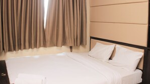 A hotel room with a large bed, beige headboard, and curtains. - Comfort 1Br At Sky Terrace Apartment (Jakarta)