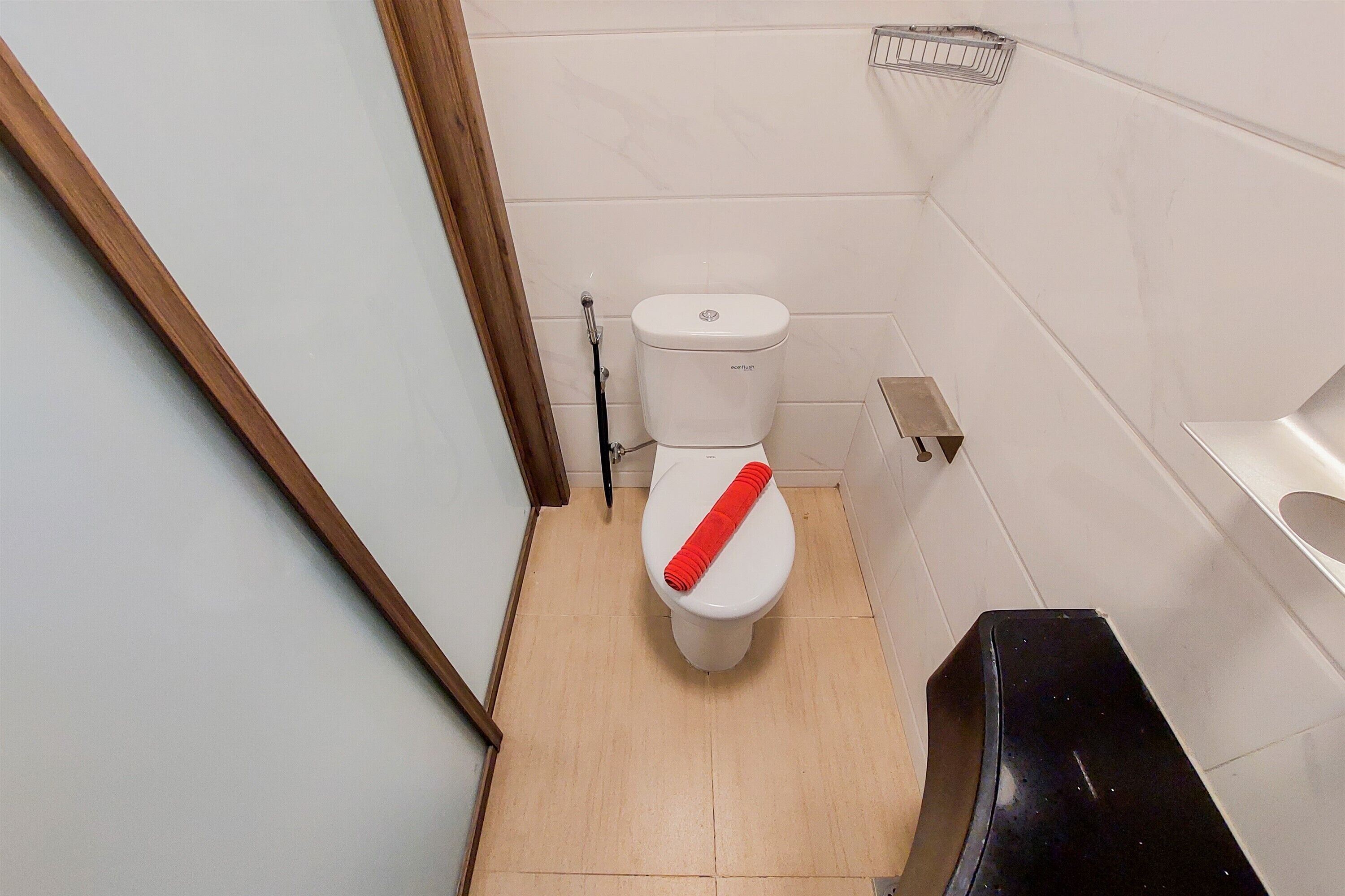 A small, clean bathroom with a toilet, a bidet, and a black trash bin.