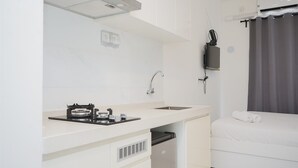Una camera d'albergo compatta con angolo cottura, un letto e una finestra con tende.