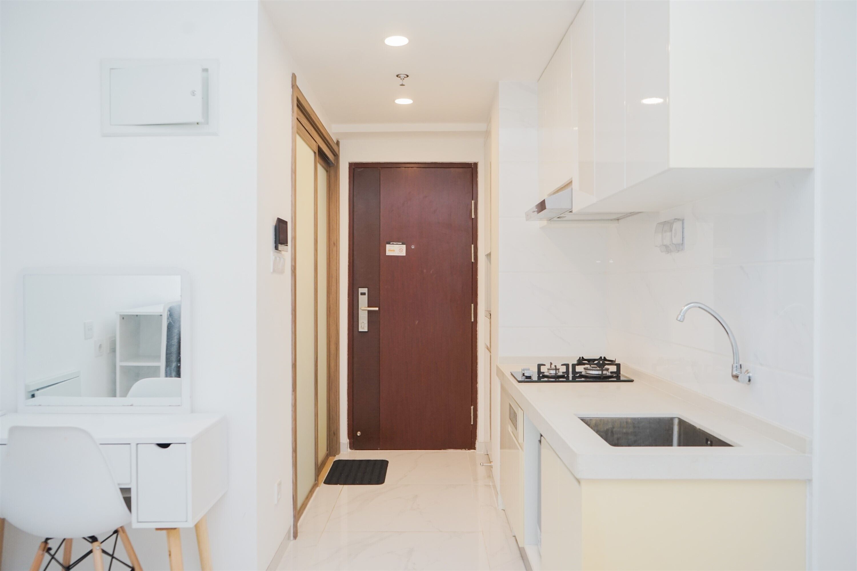 A modern kitchen with a sink, countertop, and a wooden door.
