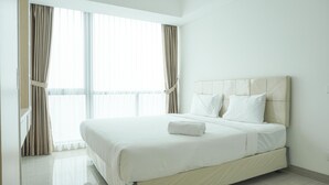 Een hotelkamer met een groot bed, een raam met gordijnen en een schoon, modern design.