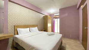 A bedroom with a wooden bed, a nightstand, a wardrobe, and a patterned wallpaper. - Cozy 3Br Furnished Apartment At Gateway Ahmad Yani Cicadas (Bandung)