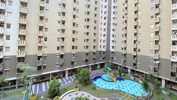 A high-rise residential building with multiple balconies, a central swimming pool, and surrounding greenery. - Cozy 3Br Furnished Apartment At Gateway Ahmad Yani Cicadas (Bandung)