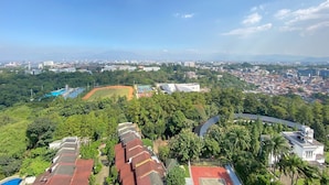 A residential area with houses, a sports field, and a clear view of a cityscape in the distance. - Cozy Studio Apartment At Beverly Dago (Bandung)