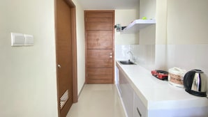A compact kitchen with a sink, a kettle, and a microwave on the countertop. - Cozy Studio Apartment At Beverly Dago (Bandung)