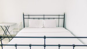 A single bed with a metal frame, white bedding, and a small white table with a chair beside it. - Nice And Cozy Studio At Paramount Skyline Serpong Apartment (Gading Serpong)