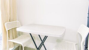 A small white table with two matching chairs, positioned against a plain wall. - Nice And Cozy Studio At Paramount Skyline Serpong Apartment (Gading Serpong)