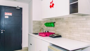 A kitchen with white cabinets, a black door, a red decorative item, and a green container. - Nice And Cozy Studio At Paramount Skyline Serpong Apartment (Gading Serpong)