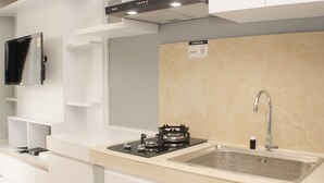 Een moderne keuken met een inbouwfornuis, spoelbak en een flatscreen televisie aan de muur.
