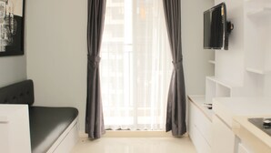 Een moderne kamer met een bed, een aan de muur bevestigde televisie en een raam met gordijnen.