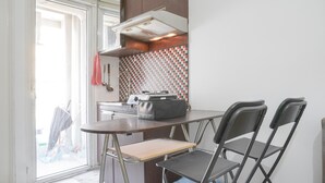 A compact kitchen with a small table and two chairs, a microwave, and a tiled backsplash. - Best Deal And Comfy 2Br At Green Pramuka City Apartment (Jakarta)