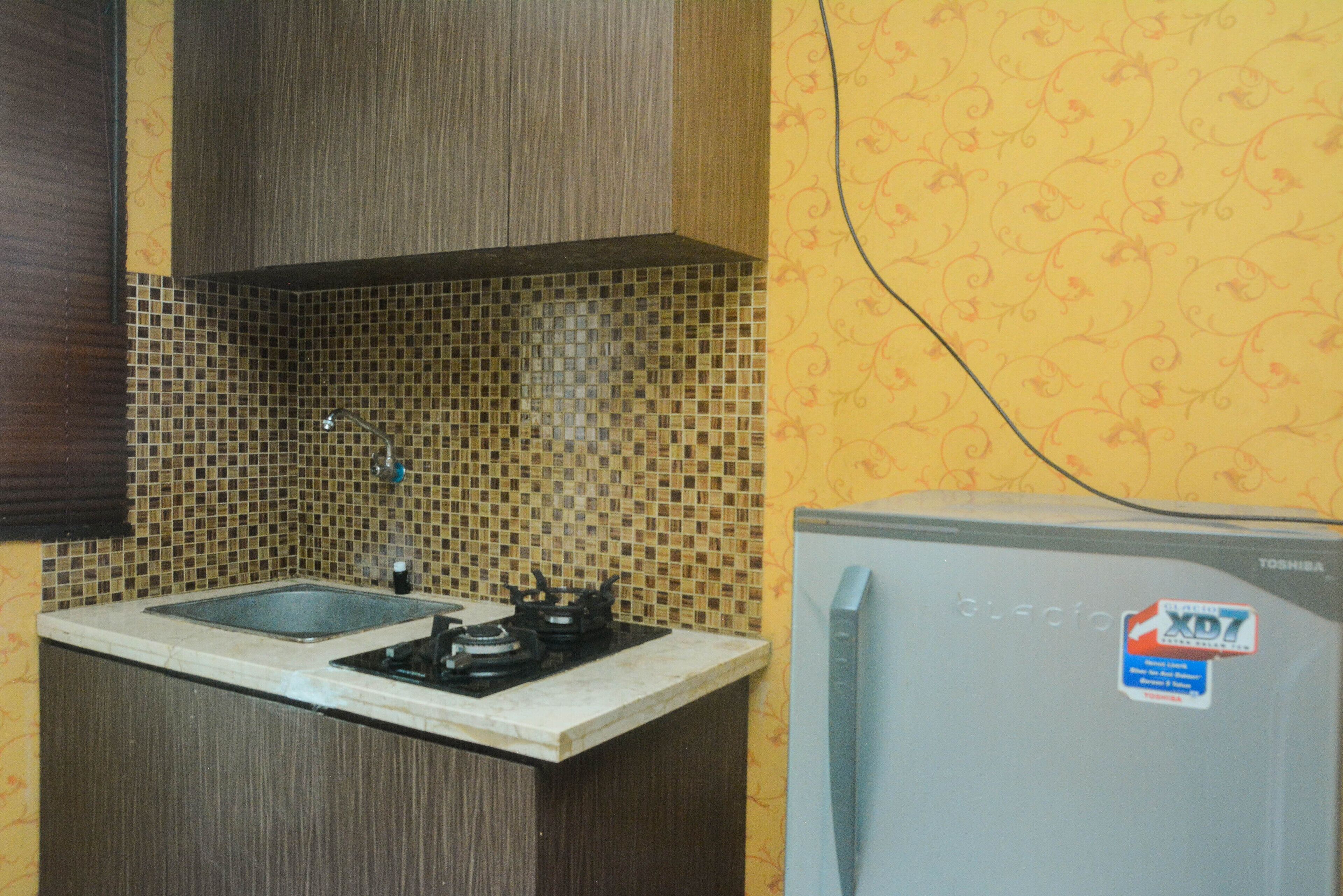 A kitchen with a tiled backsplash, a sink, a stove, and a refrigerator.