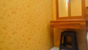 A bathroom with a patterned wallpaper, a wooden vanity, and a black stool. - Cozy Studio At Kebagusan City Apartment (Jakarta)
