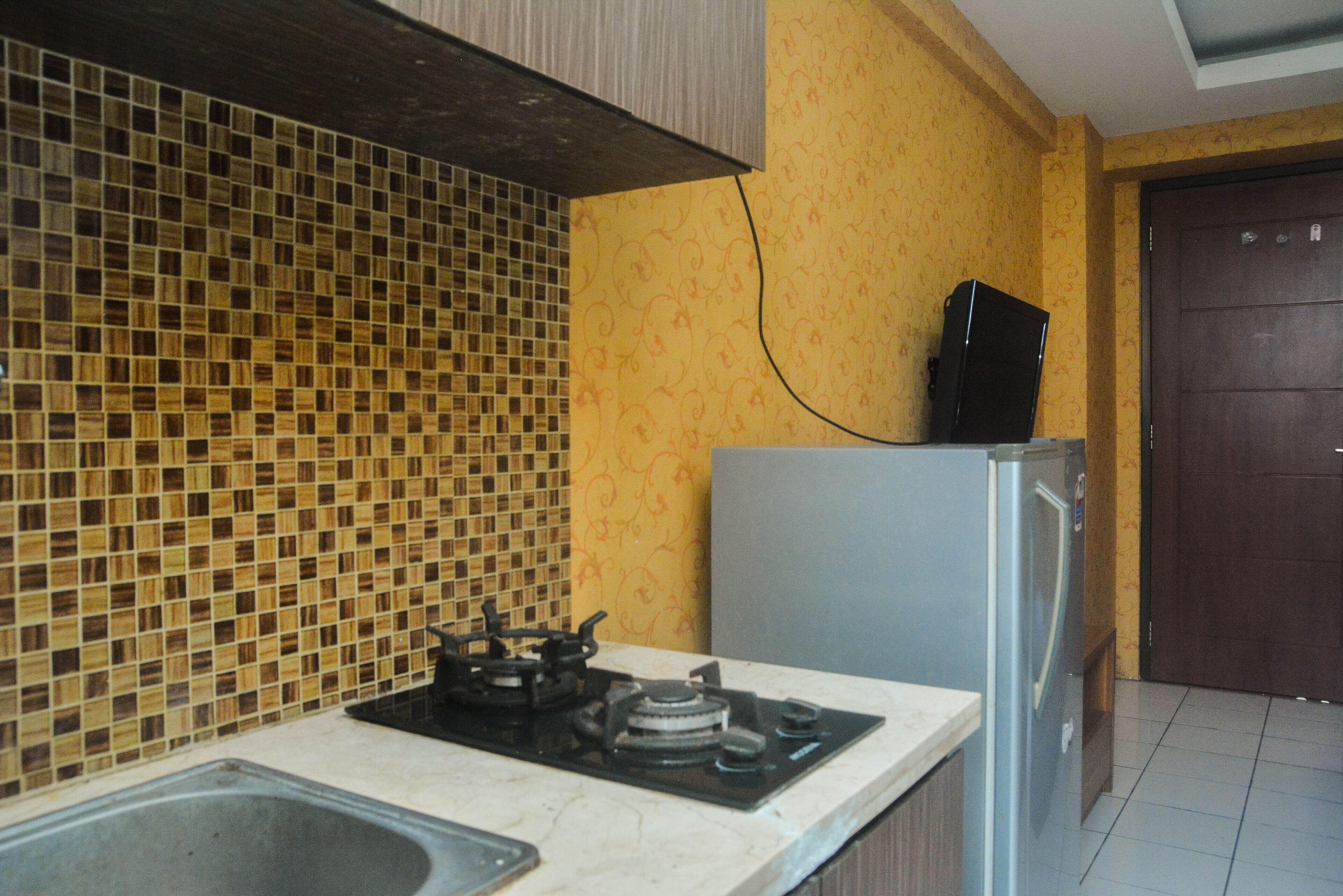 Uma cozinha com painel de azulejos, fogão a gás, geladeira e pia.