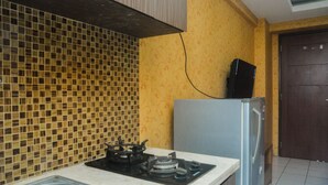 A kitchen with a tiled backsplash, a gas stove, a refrigerator, and a sink. - Cozy Studio At Kebagusan City Apartment (Jakarta)
