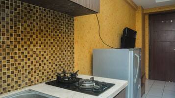 Uma cozinha com painel de azulejos, fogão a gás, geladeira e pia.
