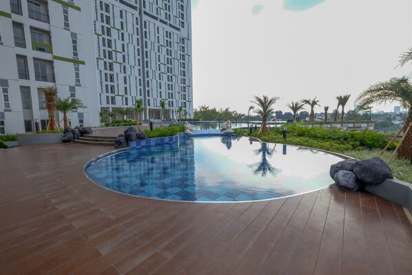 Enjoy a refreshing swim in the pool surrounded by lush greenery and a grid-like building design.