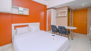A hotel room with a bed, a small table with two chairs, and a wooden door. - Warm And Cozy Stay Studio Apartment Margonda Residence 2 (Depok)