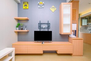 A modern living room with a TV mounted on a grey wall, wooden furniture, and decorative signs including a skull and crossbones sign.