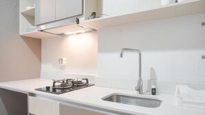 Eine moderne Küche mit Gasherd, Edelstahlspüle und weißen Schränken.