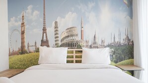 Ein Hotelzimmer mit einem großen Bett, weißer Bettwäsche und einem Wandbild berühmter Sehenswürdigkeiten.
