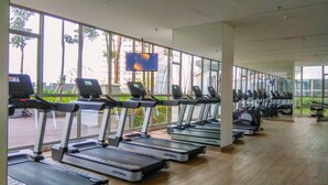 Ein Fitnessstudio mit Laufbändern, die entlang einer Wand mit großen Fenstern angeordnet sind.