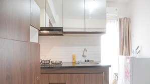A kitchen with wooden cabinets, a gas stove, a sink, and a refrigerator. - Nice And Cozy 2Br At Cinere Resort Apartment (Depok)