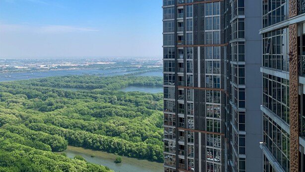 Un edifici alt amb nombrosos balcons que donen a un riu i vegetació abundant.