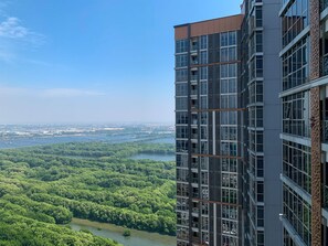 A high-rise building with multiple balconies overlooking a river and dense greenery. - Minimalist And High Floor Studio Room At Gold Coast Apartment (Jakarta)