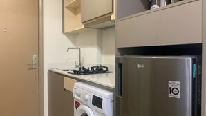 Cuina compacta amb rentadora, nevera d'acer inoxidable i un rentaplat amb aixeta.