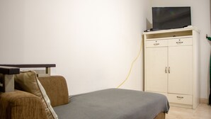 Una habitació amb un llit, una televisió sobre un moble i un armari.