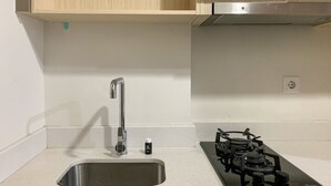 Cuina amb un vàter d'acer inoxidable, fogó a gas i armaris de fusta.