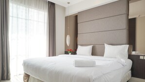 A large bed with white linens, a headboard, and a bedside table with a lamp. - Cozy Stay And Tidy 1Br At The Bellezza Apartment (Jakarta)