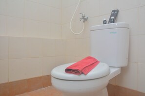 Ein Badezimmer mit Toilette, Duschkopf und weißem Toilettentank.