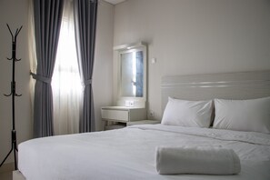 Une chambre d’hôtel avec un lit bien fait, une table de chevet, un miroir et un porte-manteau.