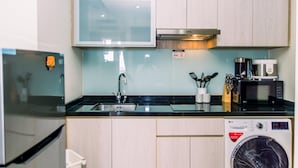 Uma cozinha moderna com frigorífico de aço inoxidável, micro-ondas embutido e máquina de lavar roupa.