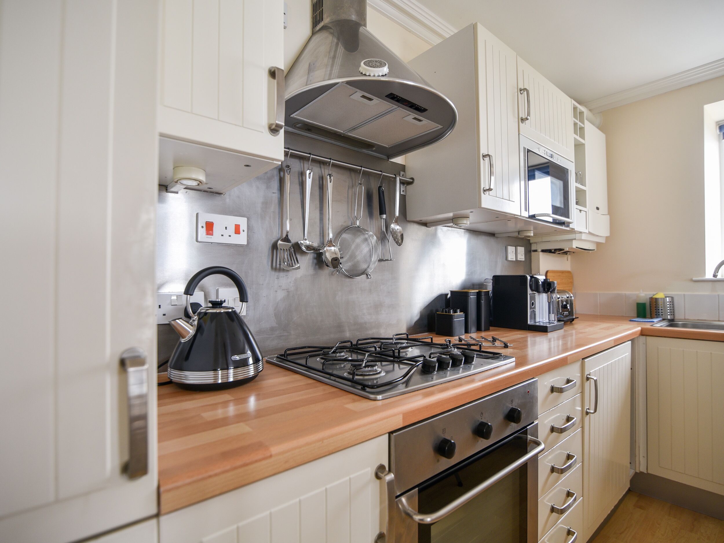 A modern kitchen with stainless steel appliances, wooden countertops, and white cabinetry.