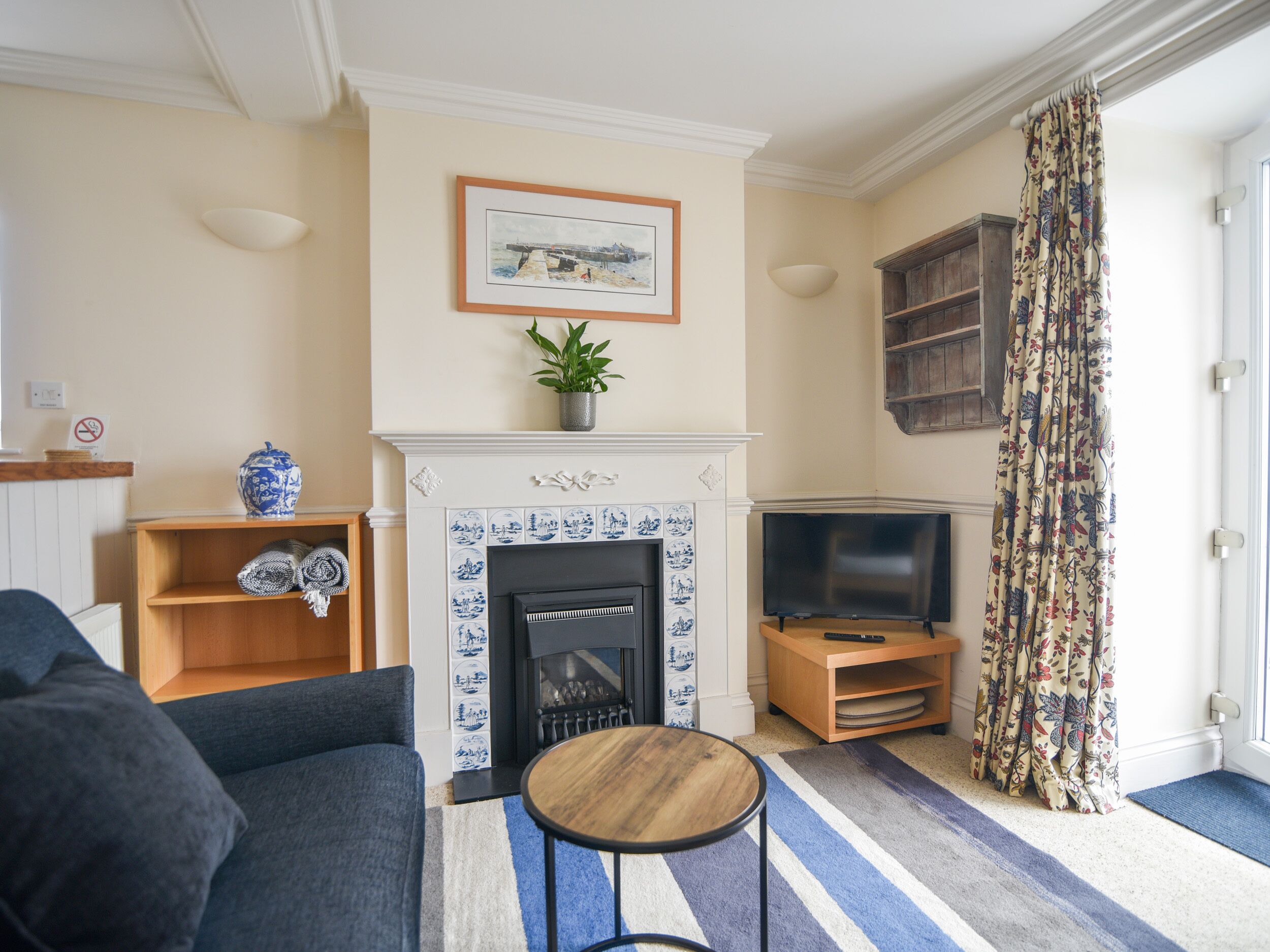 A living room with a fireplace, a television, a sofa, and a small table.